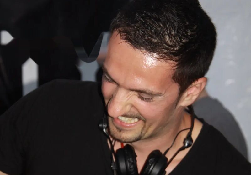 Primer plano de DEEP UNIT sonriendo, con auriculares al cuello