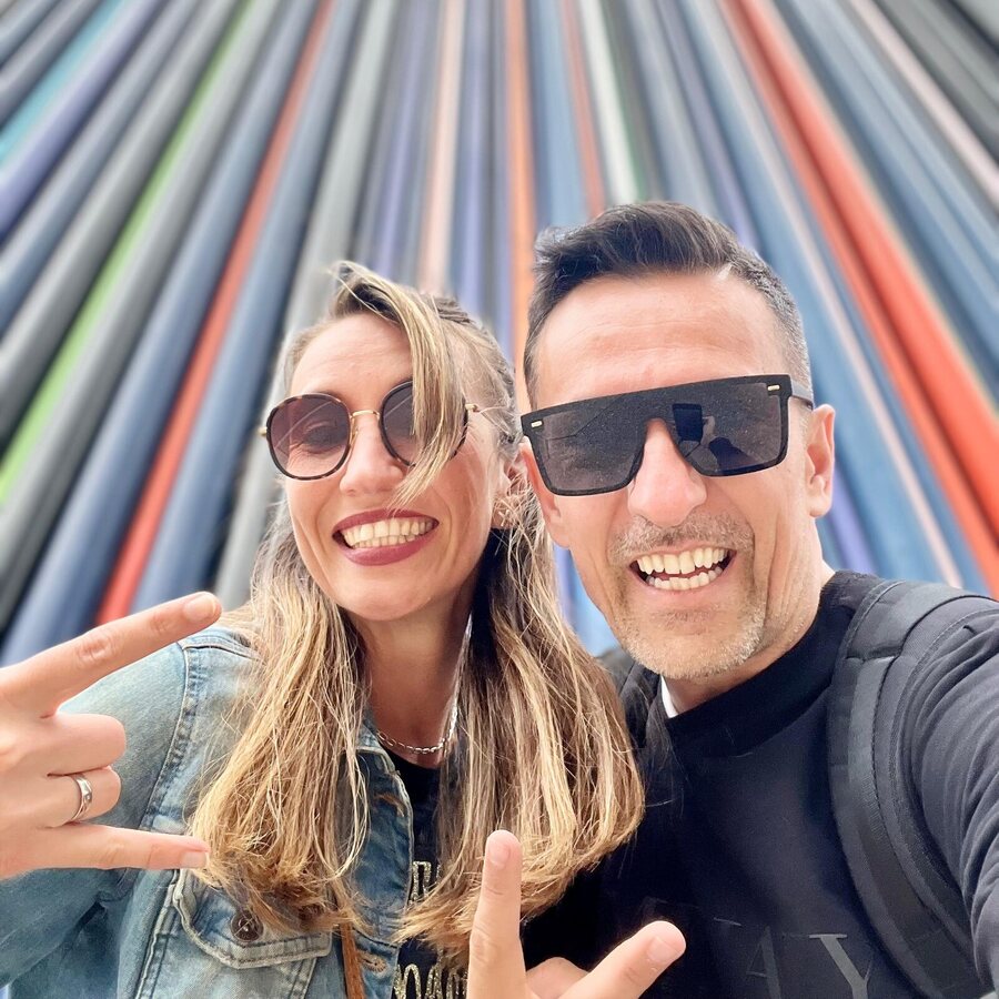 Selfie de DEEP UNIT con una amiga ante una pared de rayas de colores